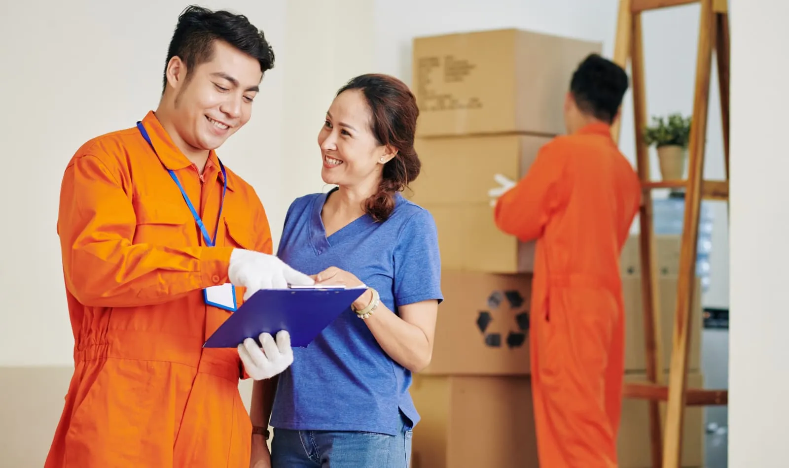 Movers in orange uniforms reviewing a checklist with a customer
