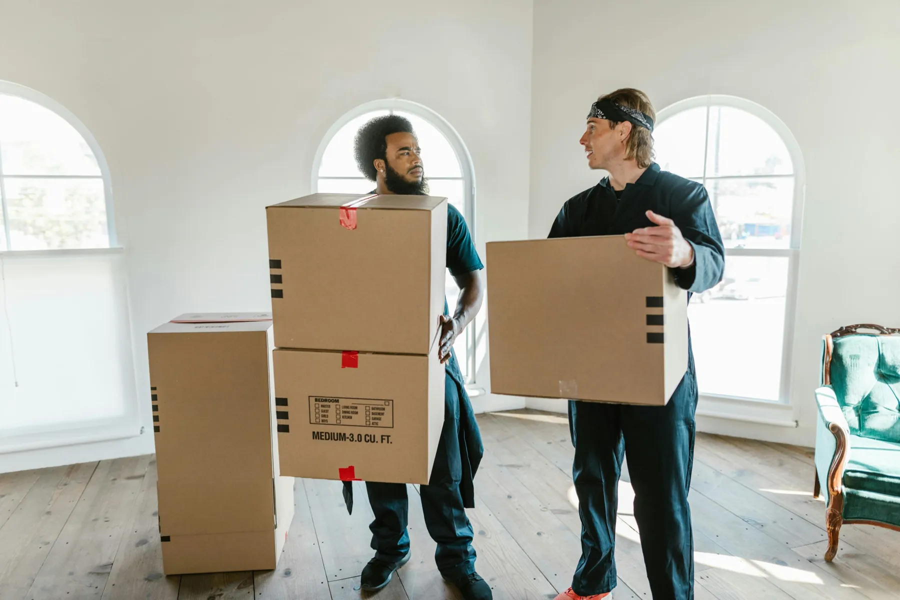 Two movers carrying boxes through an empty room